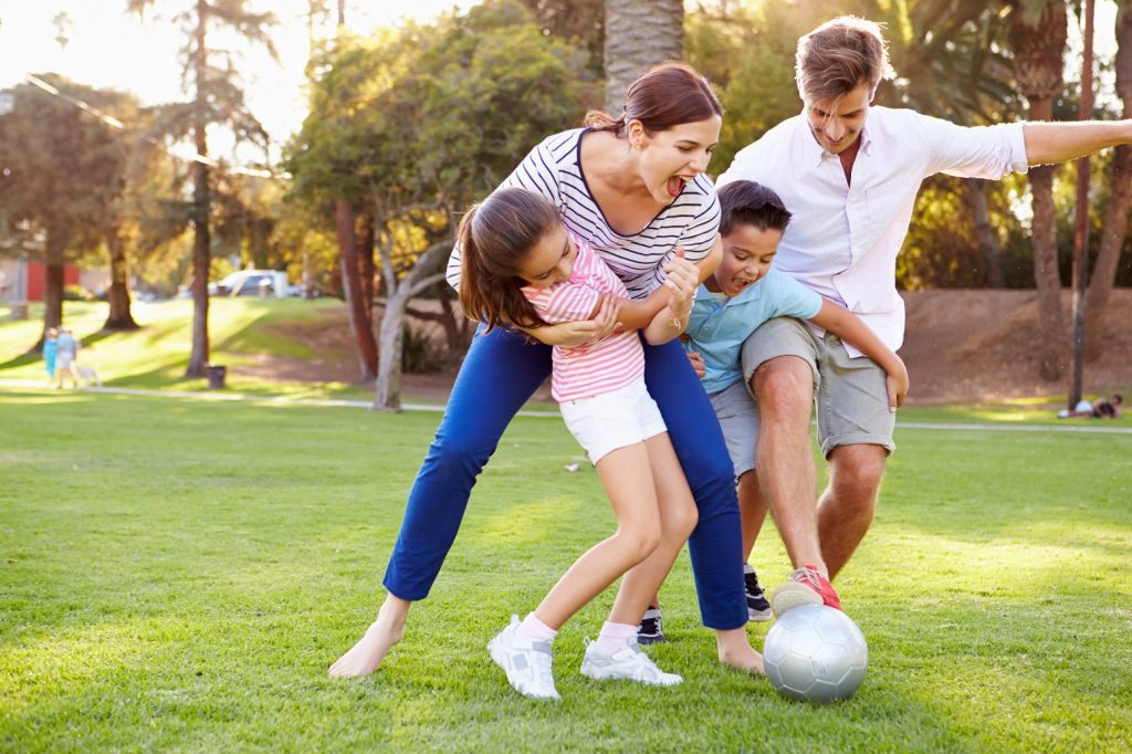 Young family playing soccer on a field
